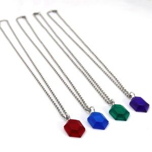 May include: Four silver necklaces with different colored gem pendants. The pendants are red, blue, green, and purple.