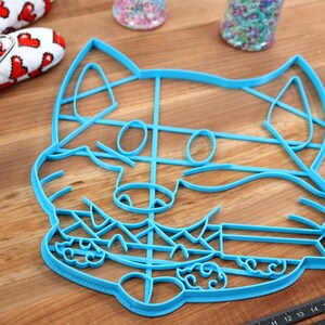 May include: A blue plastic cookie cutter shaped like a cartoon fox with a detailed face and a grid pattern on the body.