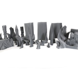 May include: A set of 3D printed gray plastic pieces for a tabletop game or miniature model. The pieces are various shapes and sizes, including spikes, pillars, and walls.