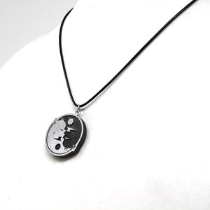 May include: A black and silver yin yang pendant necklace with a black cord.