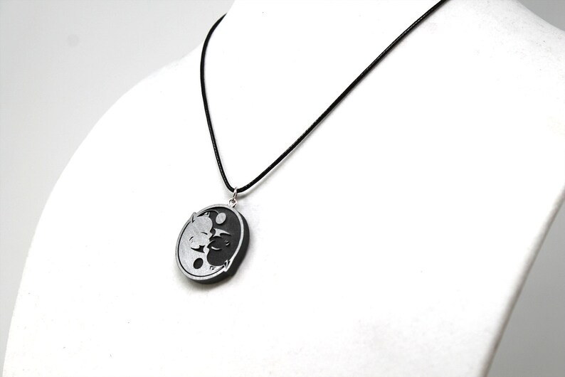 May include: A black and silver yin yang pendant necklace with a black cord.