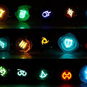 May include: A set of 15 glowing resin dice with various symbols and colors, including blue, green, orange, and red. The dice are arranged in three rows of five.