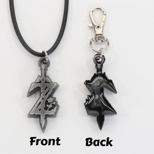May include: A silver-colored pendant necklace with a black cord and a silver-colored clasp. The pendant is a stylized sword with a design on the front and a black finish on the back. The pendant is also available as a keychain with a silver-colored clip.