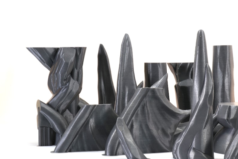 Puede incluir: Una colecci&oacute;n de esculturas abstractas impresas en 3D de color gris con una superficie lisa y texturizada. Las esculturas est&aacute;n dispuestas en fila sobre un fondo blanco.