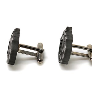 May include: A pair of silver cufflinks with black tire tread designs.
