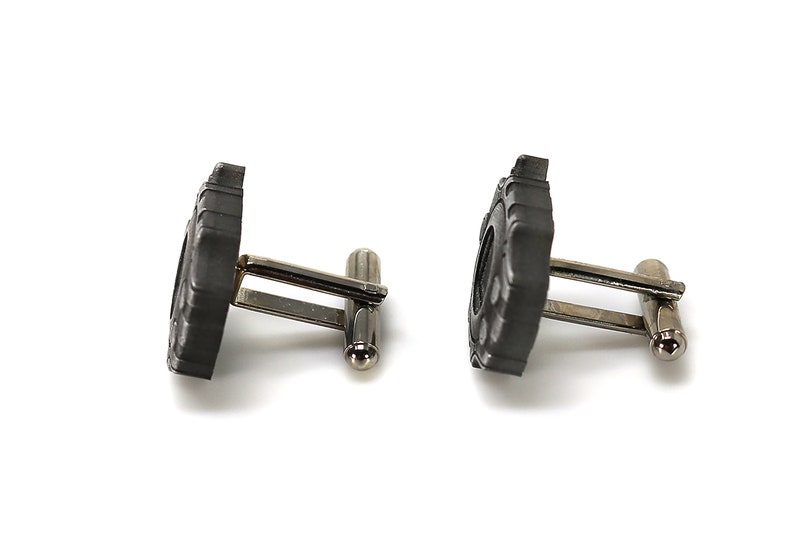 May include: A pair of silver cufflinks with black tire tread designs.