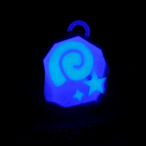 May include: A blue and white glow-in-the-dark charm with a spiral and stars design.
