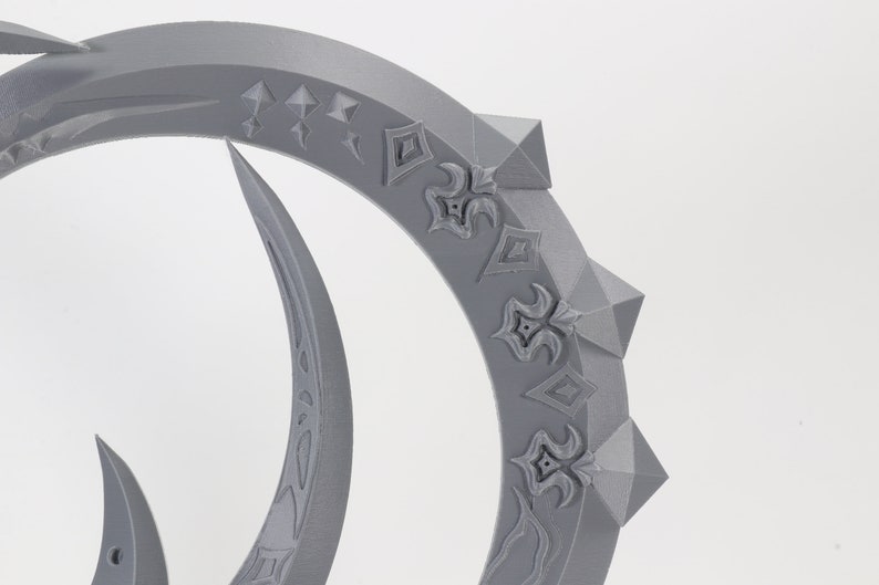 May include: A gray 3D printed ring with intricate designs and pointed edges. The ring is made of plastic and has a smooth surface.