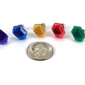 May include: Five colorful plastic gems in the shape of a hexagon with silver posts. The gems are blue, light blue, yellow, red, and green.