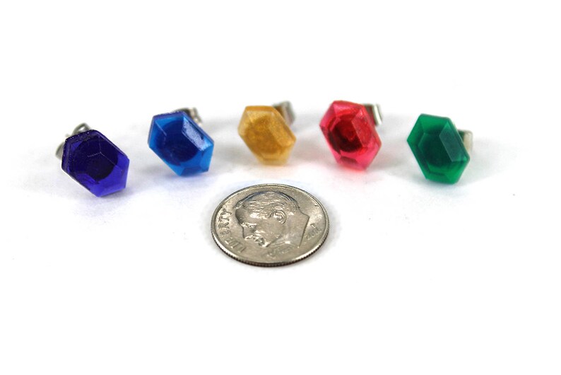 May include: Five colorful plastic gems in the shape of a hexagon with silver posts. The gems are blue, light blue, yellow, red, and green.