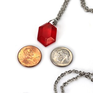 May include: A red gemstone pendant necklace on a silver chain. The pendant is about the size of a US penny.