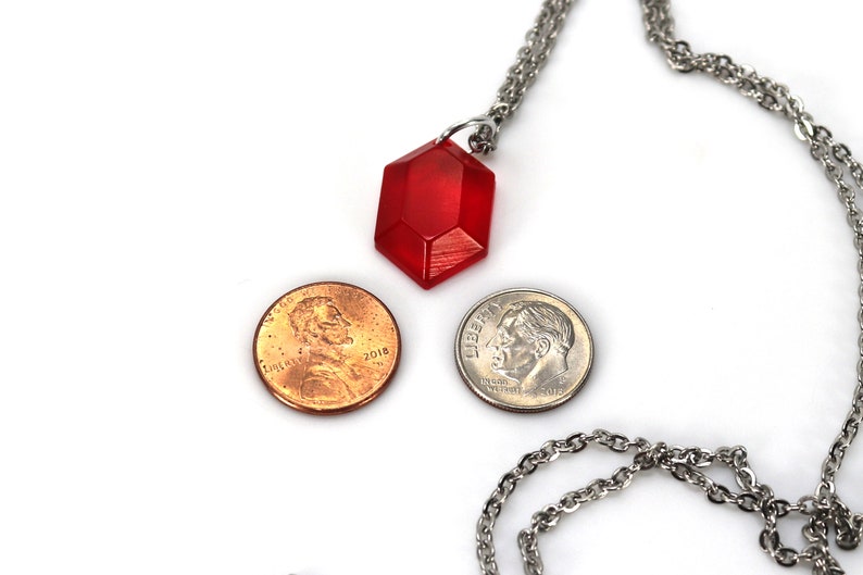 May include: A red gemstone pendant necklace on a silver chain. The pendant is about the size of a US penny.