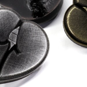 May include: Three heart-shaped metal buttons with a distressed finish. The buttons have a raised design of a broken heart.