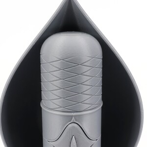May include: A gray 3D printed object with a textured surface. The object is shaped like a teardrop and has a smaller, cylindrical object inside.