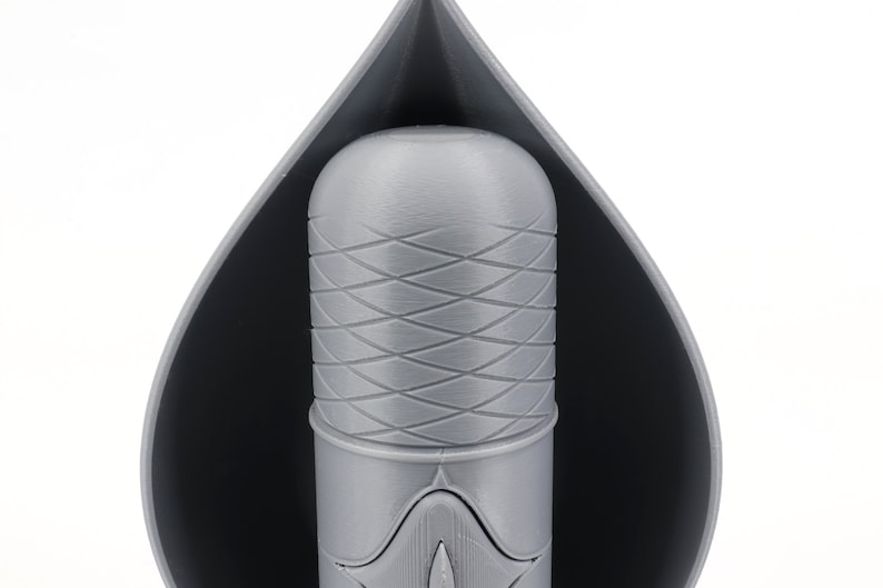 May include: A gray 3D printed object with a textured surface. The object is shaped like a teardrop and has a smaller, cylindrical object inside.