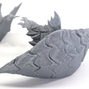 Op de afbeelding: Drie grijze 3D-geprinte drakenklauwen met een textuur.