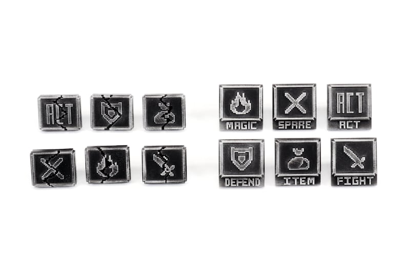 May include: Nine black and silver metal game tokens with various symbols and text, including "ACT", "FIGHT", "MAGIC", "DEFEND", "ITEM", and "SPARE".