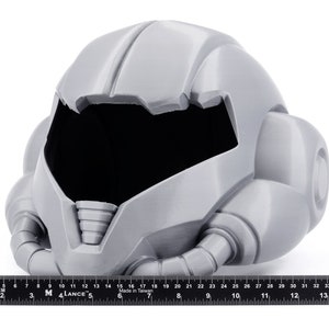 May include: A gray 3D printed helmet with a futuristic design. The helmet has a large visor and a series of tubes and pipes extending from the sides.