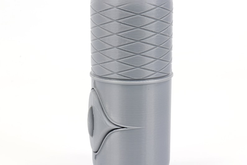 May include: A gray lightsaber hilt with a textured diamond pattern on the top section and a smooth gray section below. The hilt has a small, round button on the side.