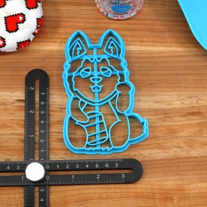 K&ouml;nnte beinhalten: Ein blauer Plastik-Ausstecher in Form eines Husky-Hundes mit Schal. Der Ausstecher ist etwa 5 cm hoch.