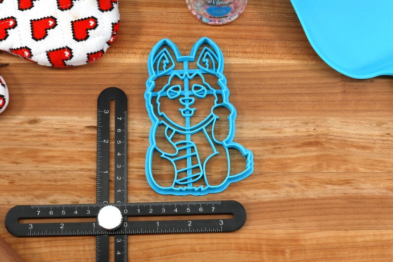 K&ouml;nnte beinhalten: Ein blauer Plastik-Ausstecher in Form eines Husky-Hundes mit Schal. Der Ausstecher ist etwa 5 cm hoch.