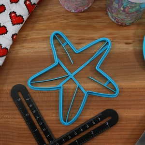 May include: A blue plastic star-shaped cookie cutter on a wooden surface.