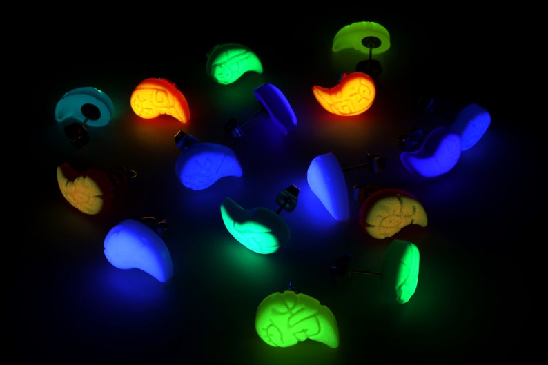 May include: A set of 12 glow-in-the-dark earrings in various colors and shapes. The earrings are made of polymer clay and have a stud back.