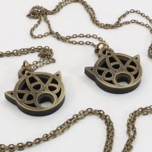 May include: Two gold-tone necklaces with matching pendants. Each pendant is a circular, openwork design with a Celtic knot pattern.