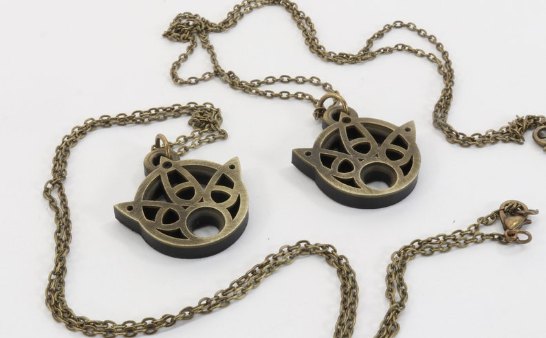 May include: Two gold-tone necklaces with matching pendants. Each pendant is a circular, openwork design with a Celtic knot pattern.