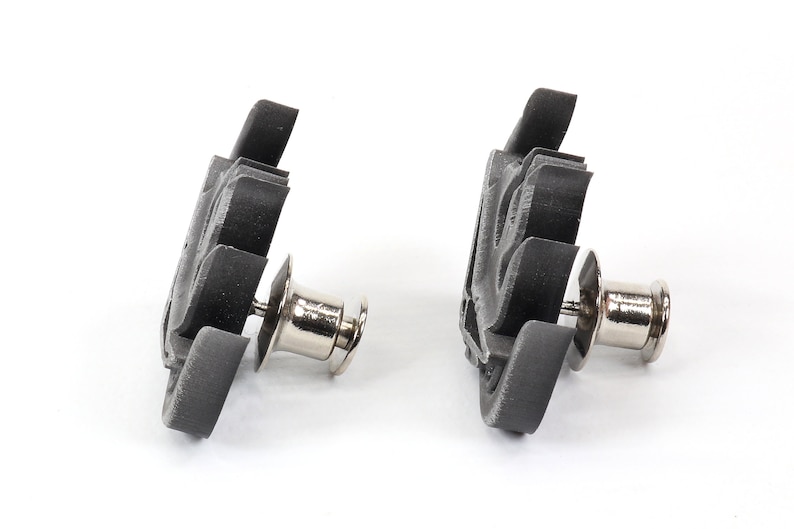 May include: Two black plastic snap fasteners with silver metal posts. The fasteners are designed to be used for attaching fabric or other materials together.