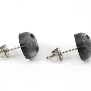 Peut inclure: Une paire de boucles d'oreilles en argent avec des dessus ronds noirs textur&eacute;s.