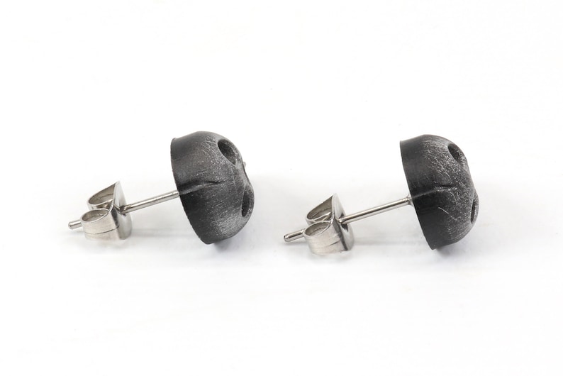 Peut inclure: Une paire de boucles d'oreilles en argent avec des dessus ronds noirs textur&eacute;s.