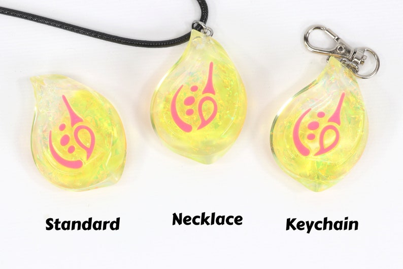 May include: Three yellow iridescent glass pendants with a pink design. The pendants are shown in three different styles: standard, necklace, and keychain.