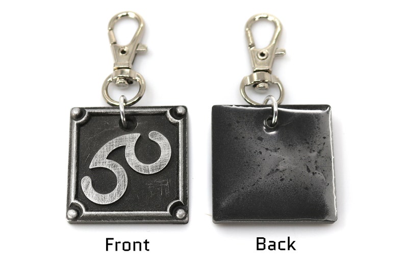 May include: A silver metal keychain with a black square charm. The front of the charm has a silver number 30 on it. The back of the charm is plain.