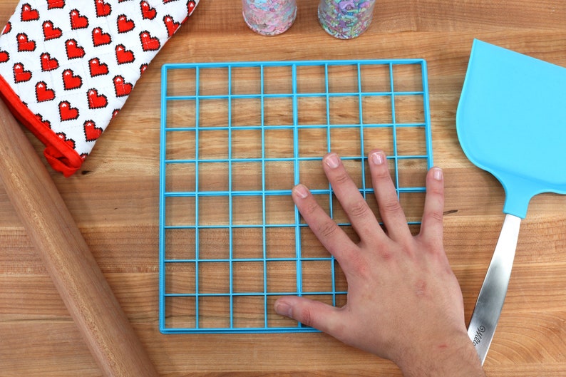 May include: A blue plastic baking sheet with a grid pattern. The sheet is 12 inches by 12 inches and has 36 squares.