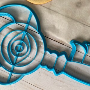 Op de afbeelding: Een blauwe plastic koekjesvormer in de vorm van een gestileerde schorpioen met een gedetailleerd ontwerp.