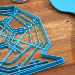 May include: A blue plastic snowflake cookie cutter on a wooden surface. A blue spatula with a silver handle is also in the image.