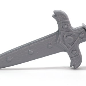 May include: A gray plastic dagger with a detailed, ornate handle. The blade is pointed and has a textured surface.