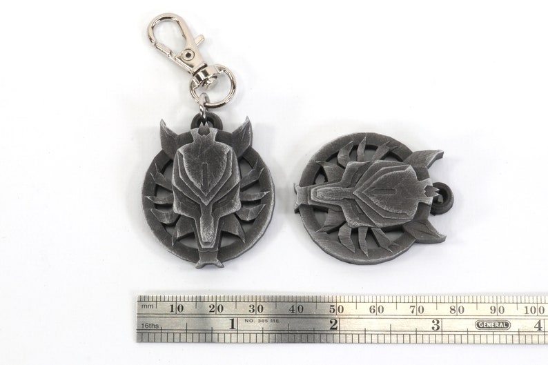 Op de afbeelding: Twee zilverkleurige metalen sleutelhangers met een wolfskopontwerp. De sleutelhangers zijn ongeveer 4 cm in diameter en hebben een gedetailleerd wolfskop met een getextureerd oppervlak.
