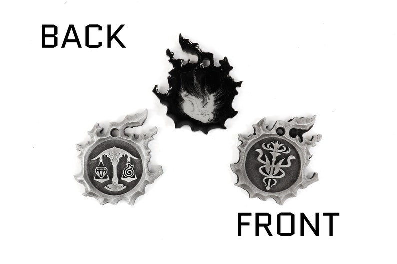 May include: Three silver metal charms with a black and white design. The charms are shaped like a flame, a scale, and a flower. The back of the charms is blank. The front of the charms has a design on it. The charms are labeled "BACK" and "FRONT".