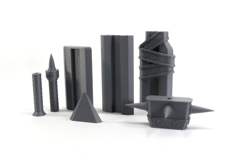 May include: A set of six grey 3D printed objects, including a spiked hammer, a pyramid, two tall rectangular blocks, and two smaller spiked objects.