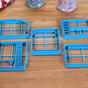 May include: Five blue plastic cookie cutters shaped like different video game cartridges.
