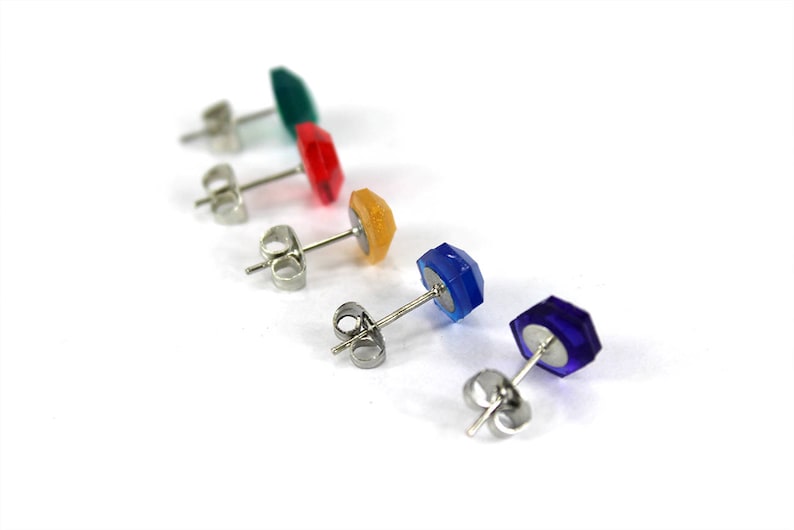 May include: Five pairs of stud earrings with different colored gemstones. The earrings are silver and have a post back.