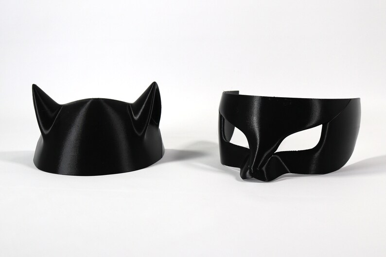 May include: Two black cat masks, one with ears and the other with a more traditional eye mask design.
