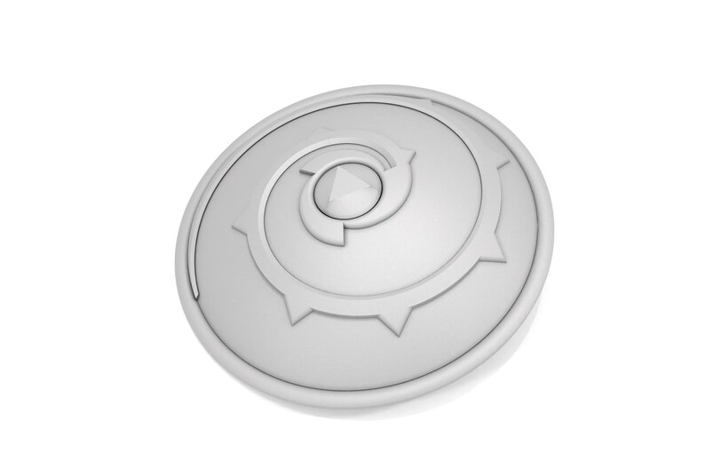 Puede incluir: Un escudo circular blanco con un dise&ntilde;o en espiral y un centro puntiagudo. El escudo tiene un borde elevado y una superficie texturizada.