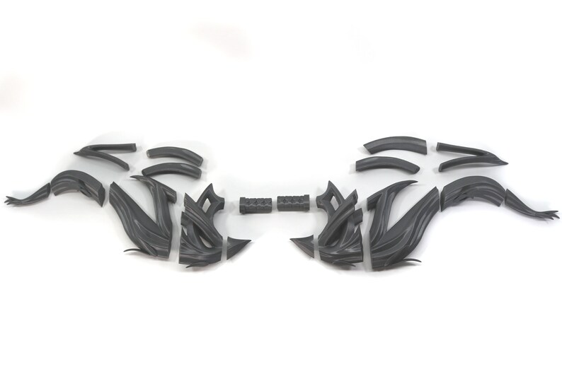 May include: A set of 16 gray plastic pieces that can be assembled into a decorative design. The pieces are shaped like curves and angles.