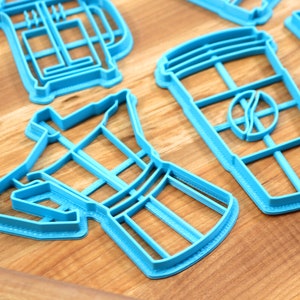 May include: A set of blue plastic cookie cutters shaped like a coffee pot, a coffee cup, and a french press.