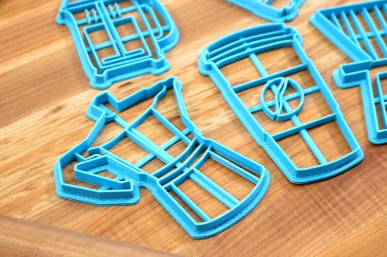 May include: A set of blue plastic cookie cutters shaped like a coffee pot, a coffee cup, and a french press.