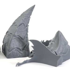 Op de afbeelding: Drie grijze 3D-geprinte stukken van een drakenkop, een is een grote hoorn, een is een kleinere hoorn en de derde is de kaak met tanden.