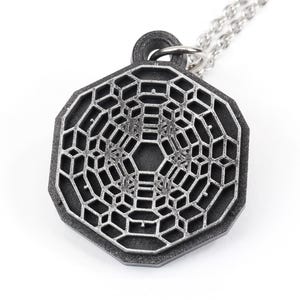 May include: A silver-toned pendant necklace featuring a geometric, octagonal design with a detailed, intricate pattern. The pendant is made of metal and has a matte finish.